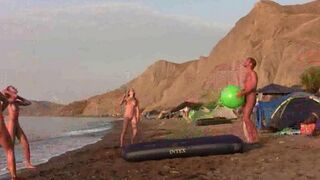 A group of nudists play badminton naked on the beach