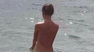 Nudists are having fun on the bare beach without clothes