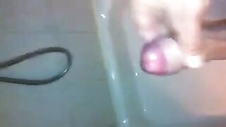 The kid caresses his dick under the shower jet