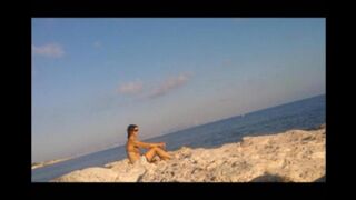 A girl is basking in the sun naked on the beach