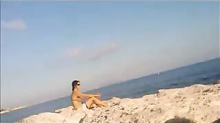 A girl is basking in the sun naked on the beach