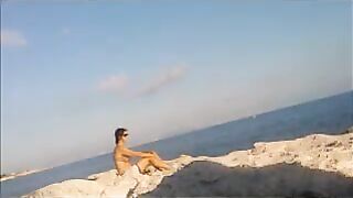 A girl is basking in the sun naked on the beach