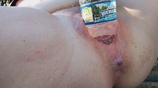 A girl reached the peak of pleasure while indulging in outdoor self-pleasure with a water bottle